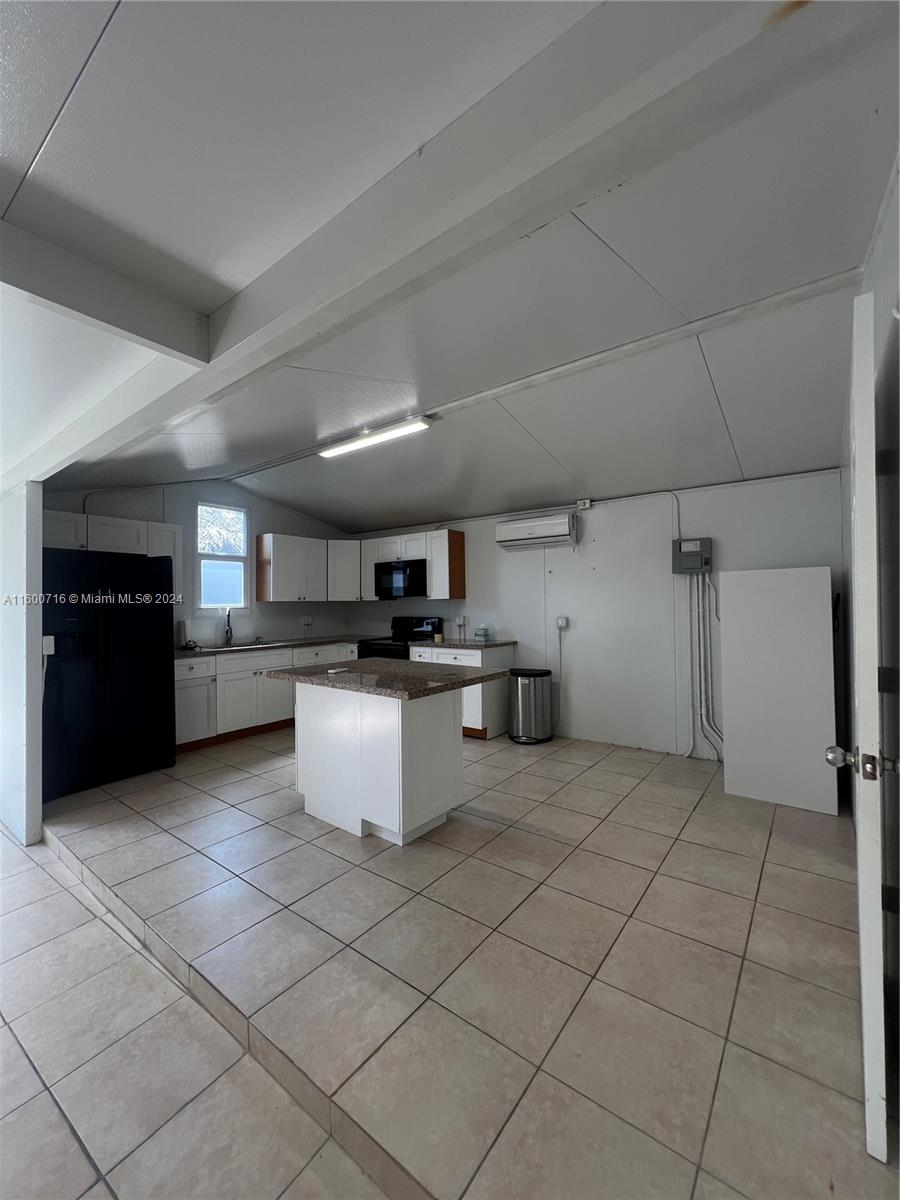 a kitchen with kitchen island granite countertop a refrigerator and a stove top oven