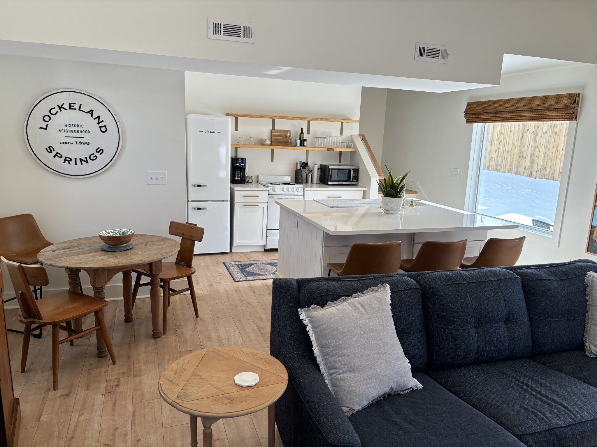 a living room with furniture a clock on wall and a window