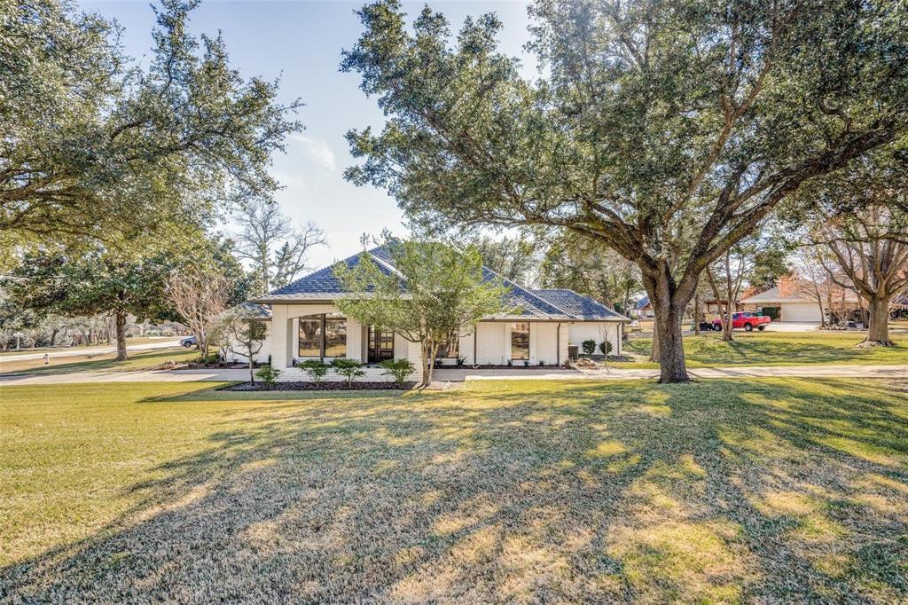 a view of a house with a yard and large trees