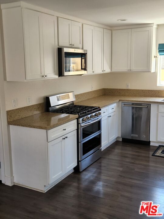 a kitchen with granite countertop white cabinets and black appliances