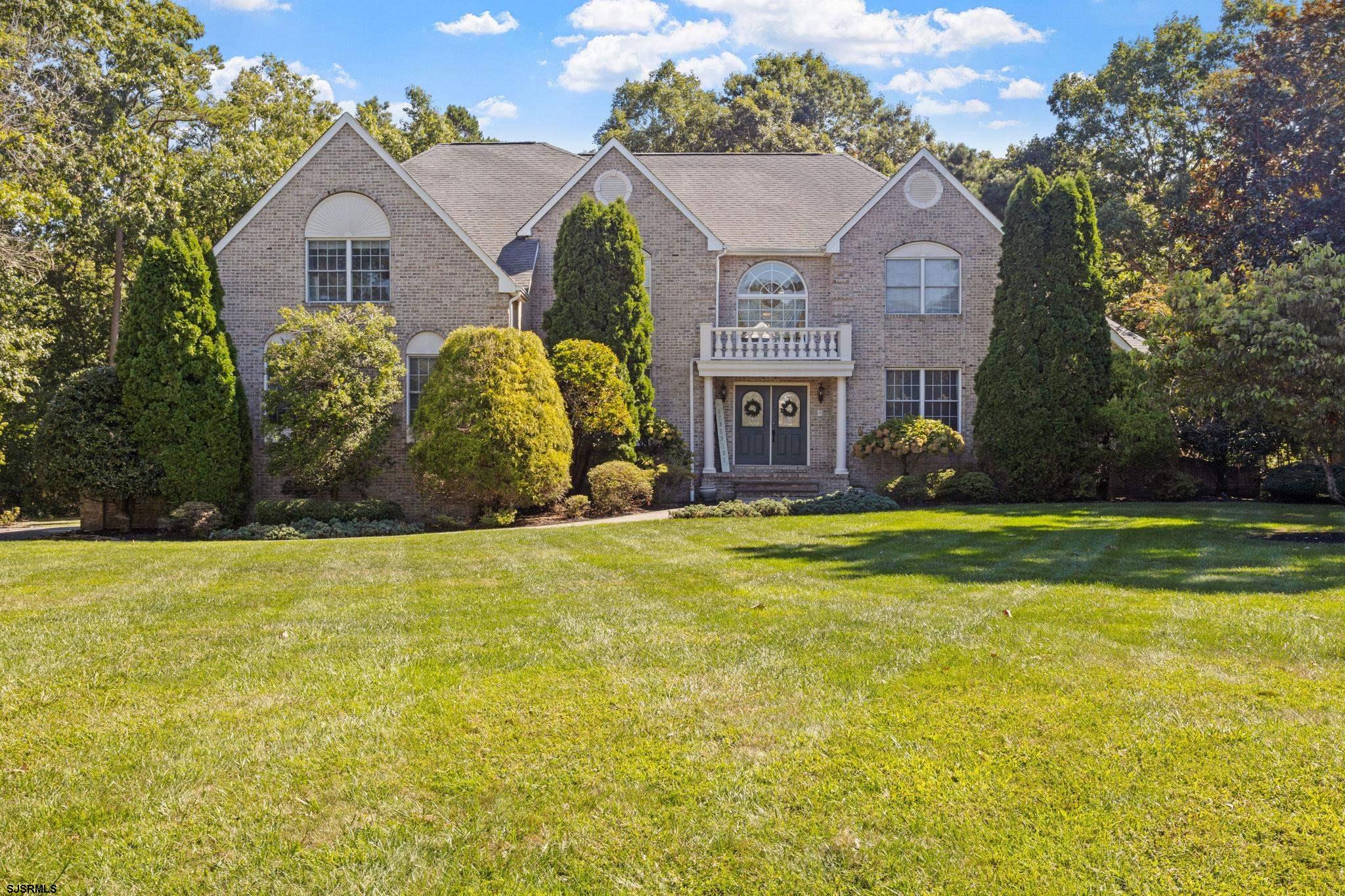 a view of a big house with a big yard and large trees