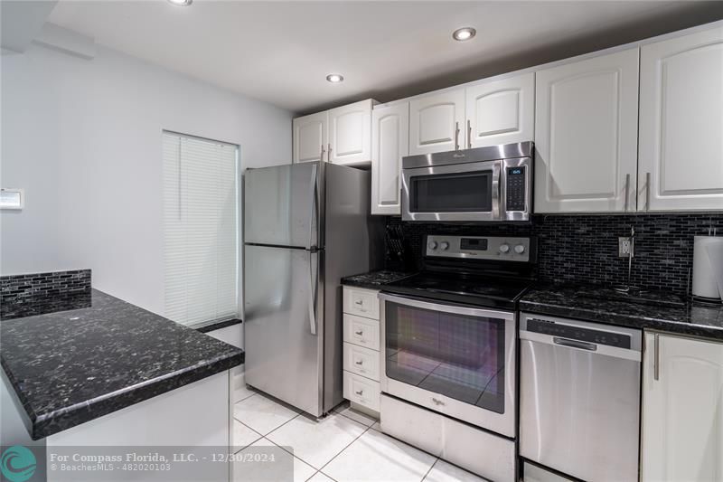 a kitchen with granite countertop a refrigerator stove and microwave