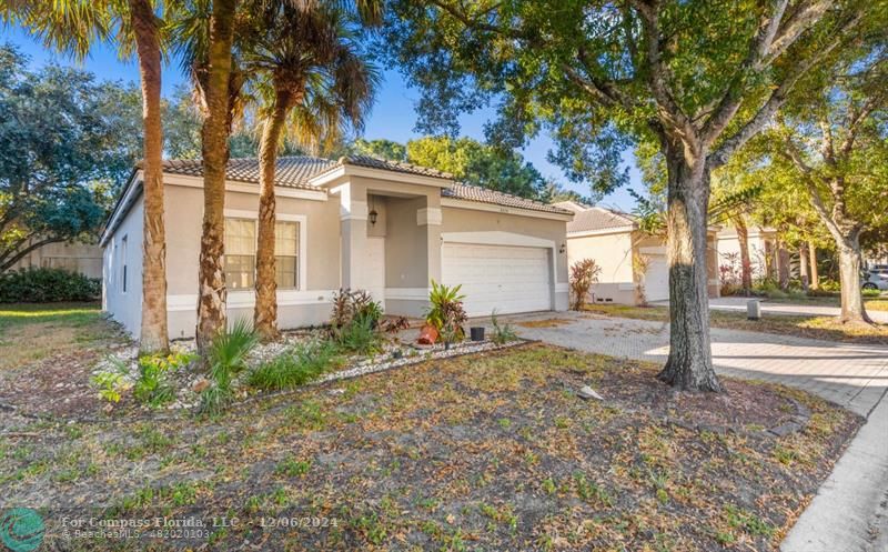 a view of a house with a small yard and palm trees