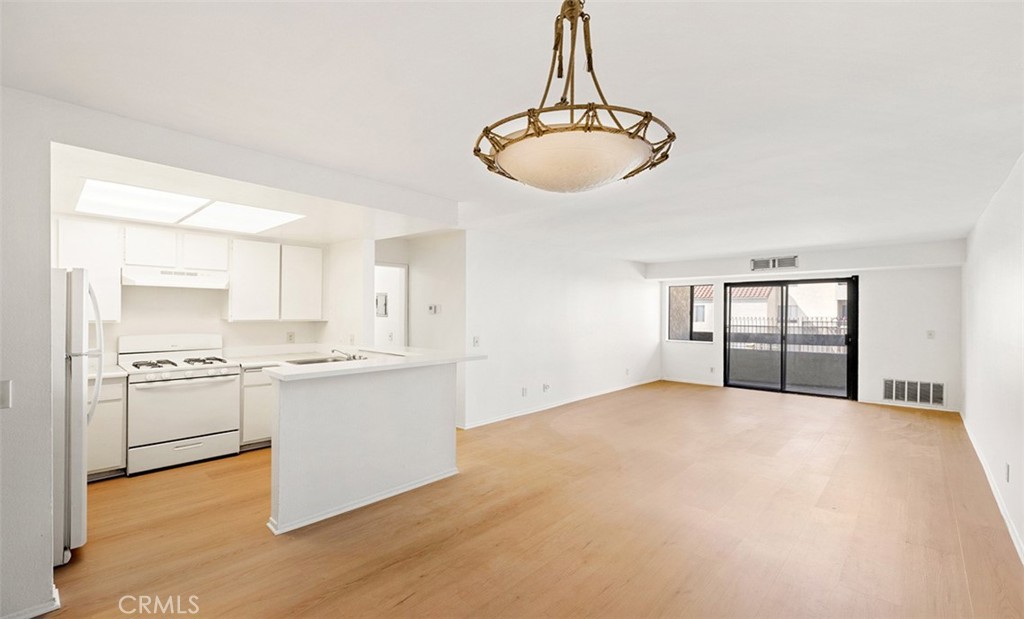 a view of a kitchen with a sink and dishwasher a stove top oven with wooden floor