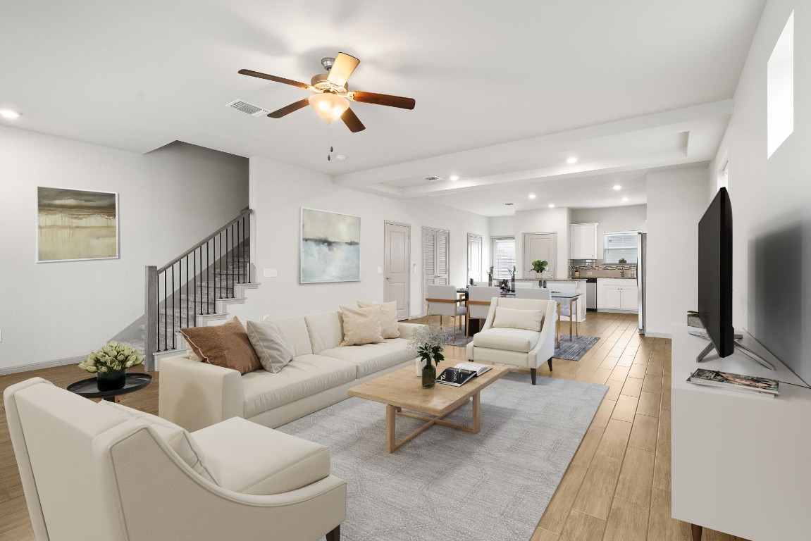 a living room with furniture and a flat screen tv with kitchen view