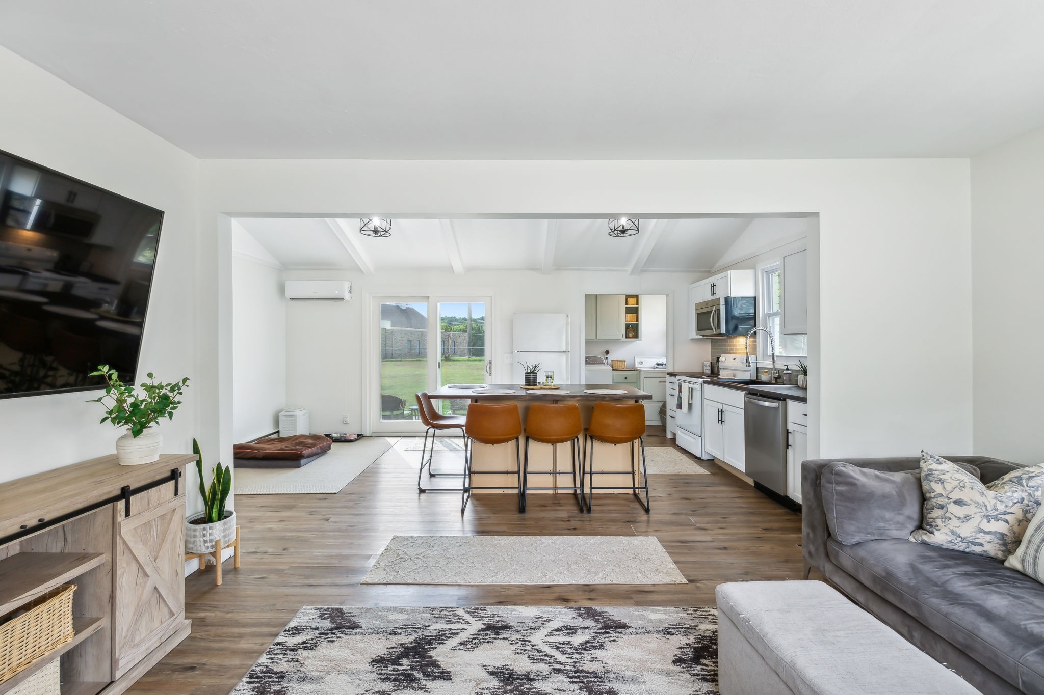 a living room with furniture kitchen view and a flat screen tv