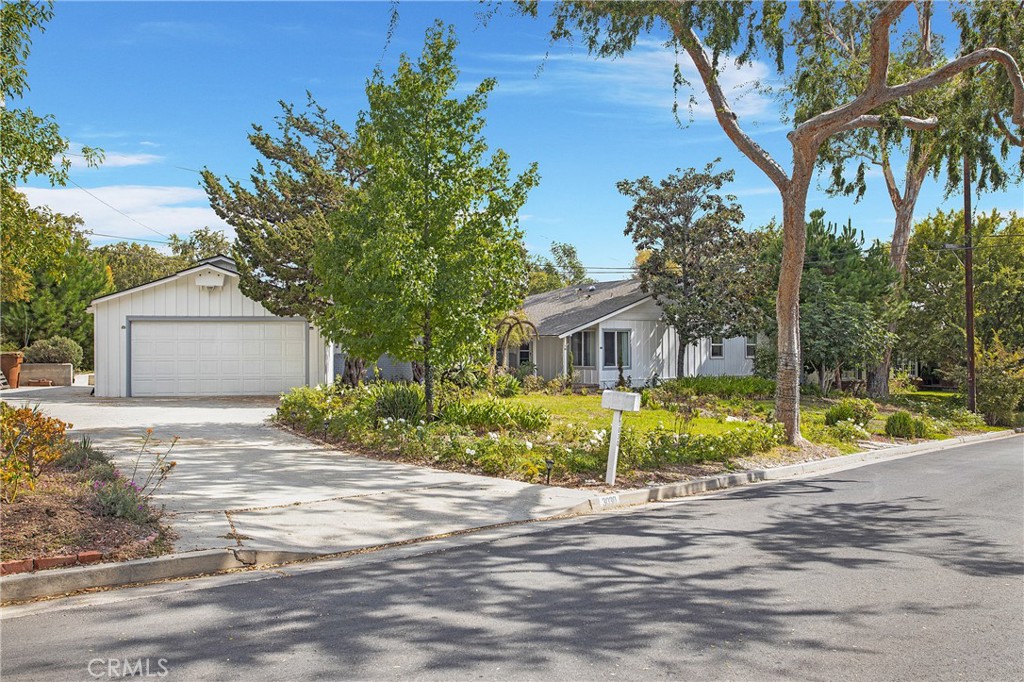 a front view of a house with a garden and trees