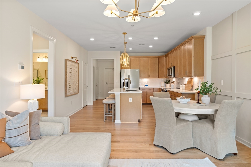 a living room with couches and kitchen view with wooden floor