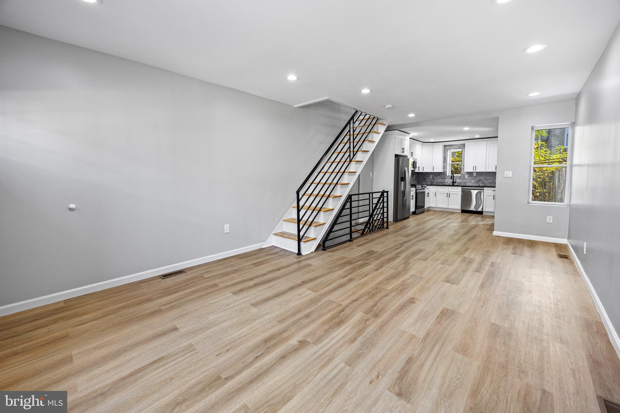 a view of an empty room with wooden floor stairs and a window