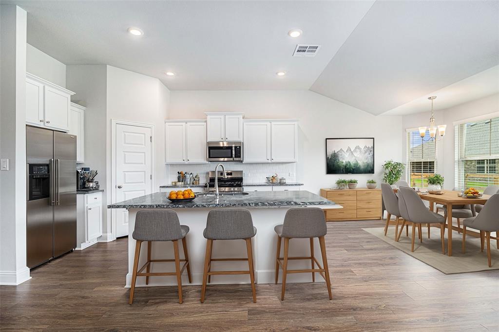 a kitchen with stainless steel appliances granite countertop a dining table chairs stove refrigerator and cabinets