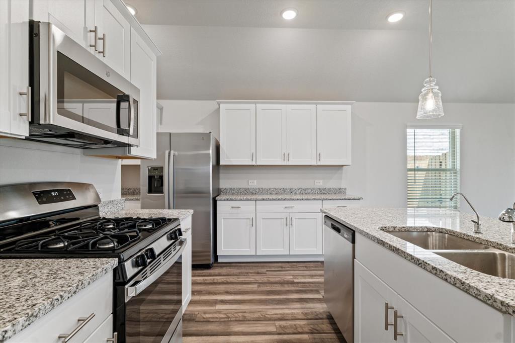 a kitchen with stainless steel appliances granite countertop a sink stove microwave and refrigerator