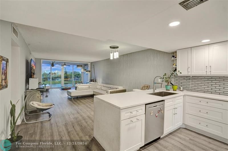 a kitchen with a sink dishwasher a stove and white cabinets with wooden floor