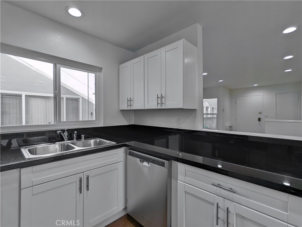 a kitchen with granite countertop white cabinets and black appliances