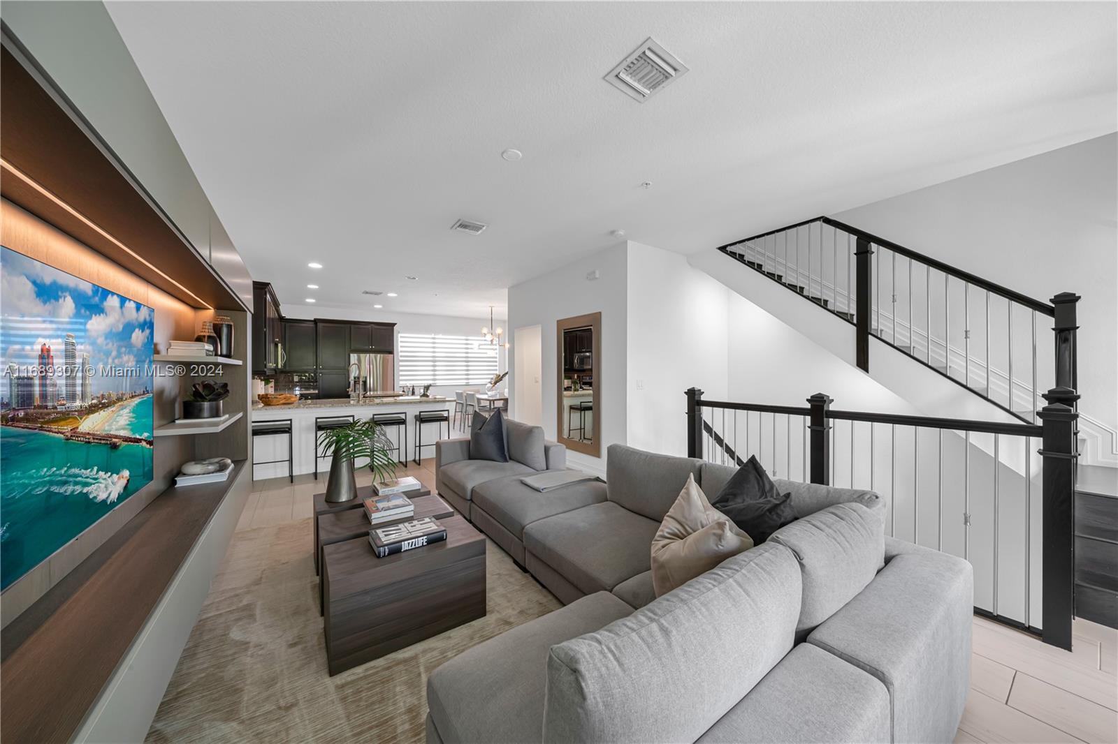 a living room with furniture kitchen view and a wooden floor