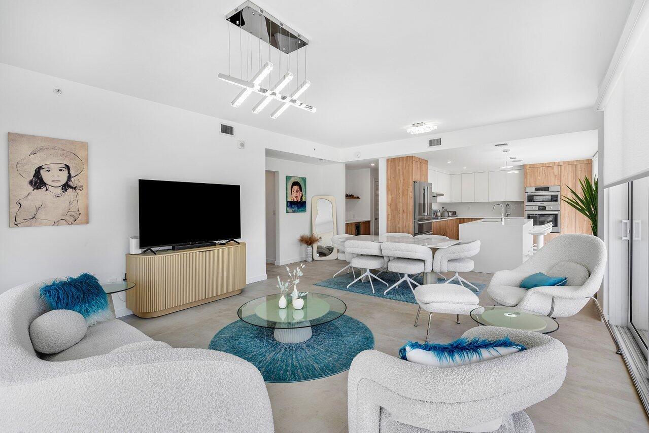 a living room with furniture a flat screen tv and kitchen view