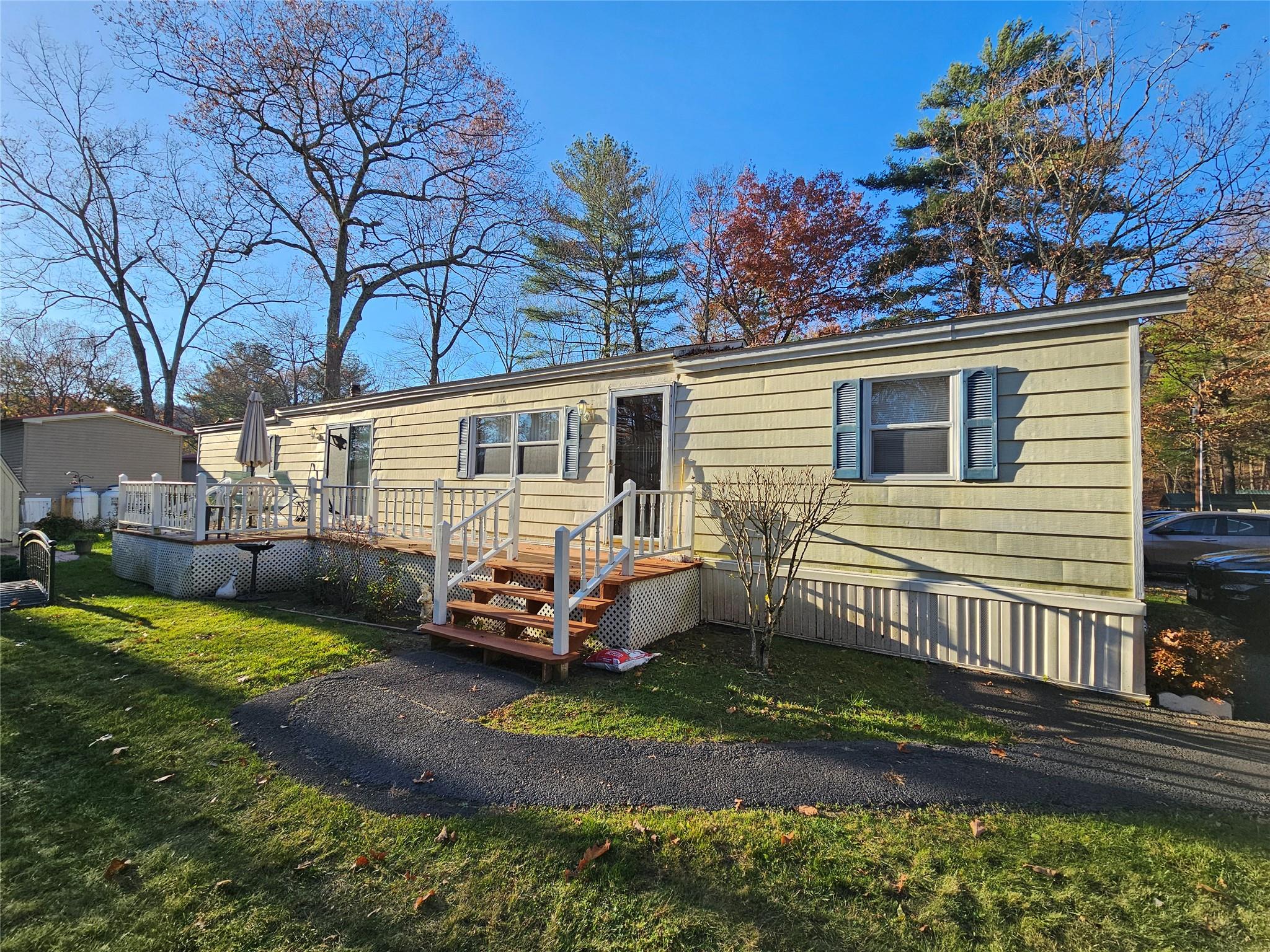 Manufactured / mobile home with a wooden deck and a front yard