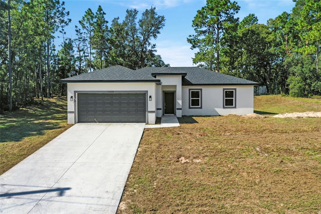 a front view of a house with yard garage and trees