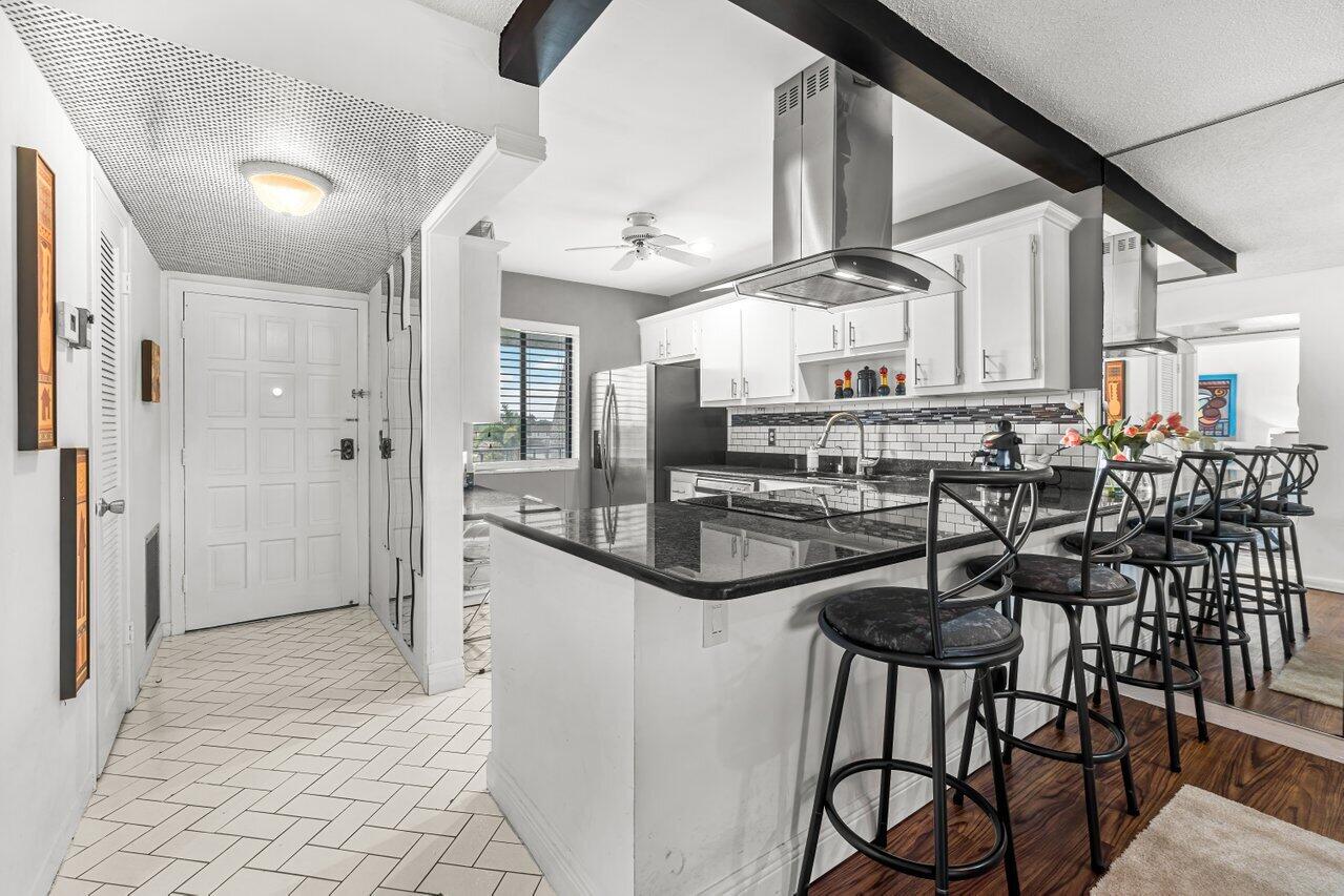 a kitchen with stainless steel appliances kitchen island granite countertop a table chairs sink and cabinets