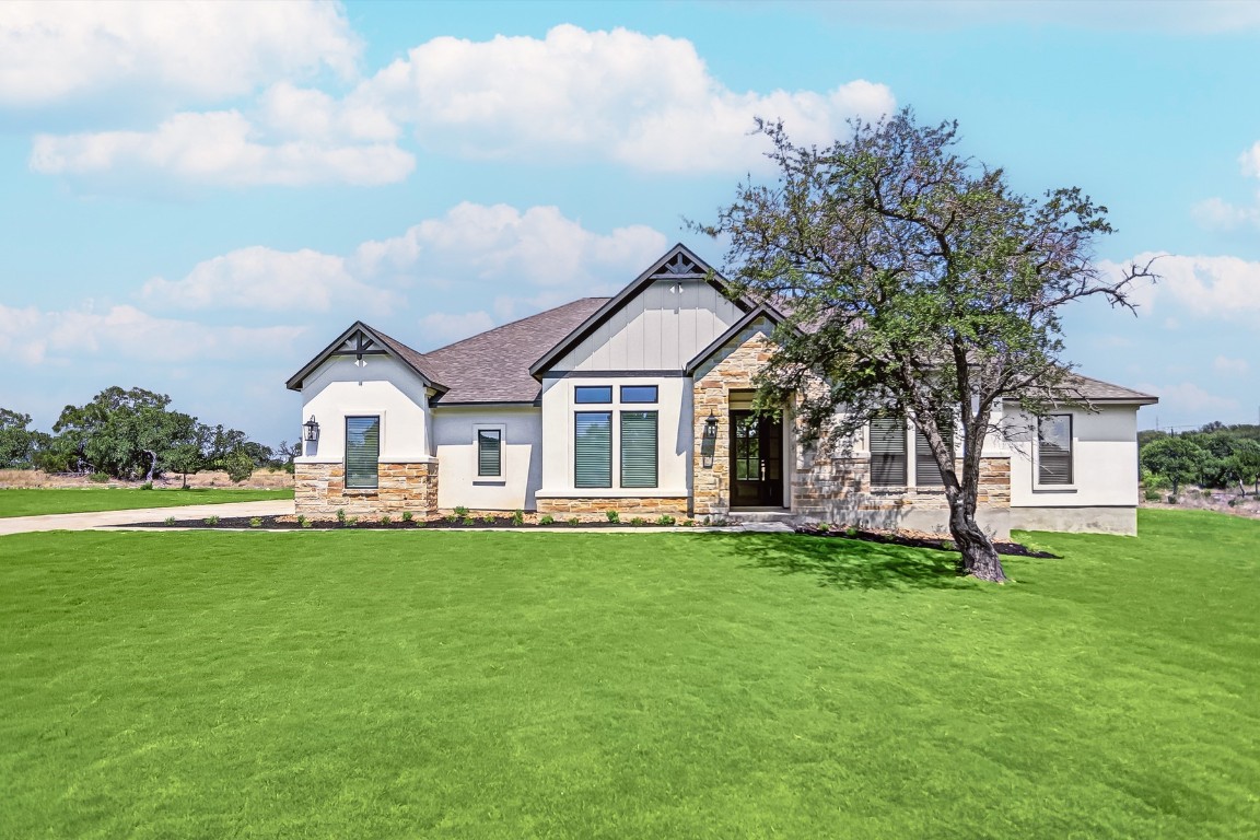 a front view of a house with a garden and trees