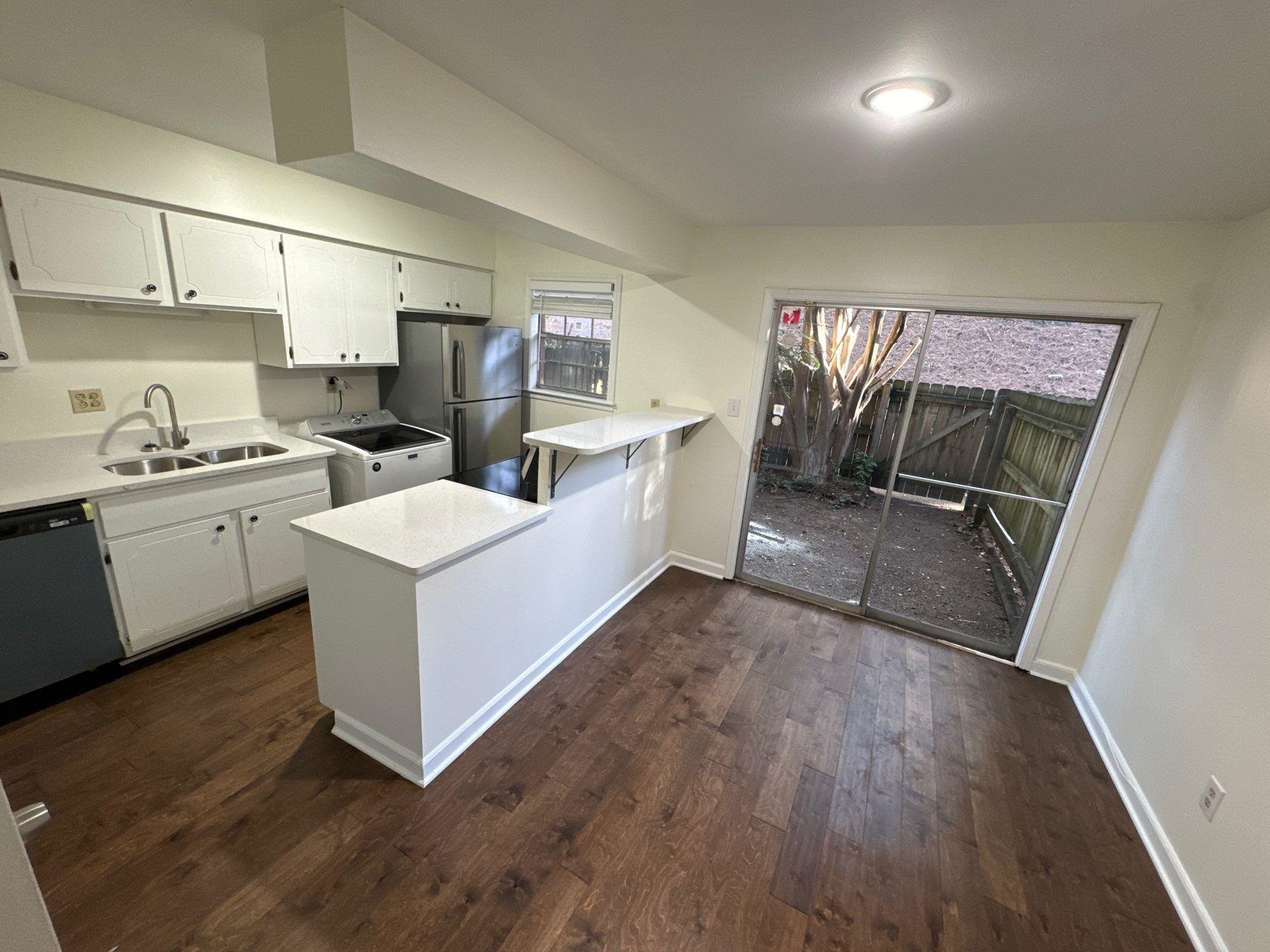 Kitchen with white cabinets, kitchen peninsula, stainless steel appliances, dark hardwood / wood-style floors, and sink