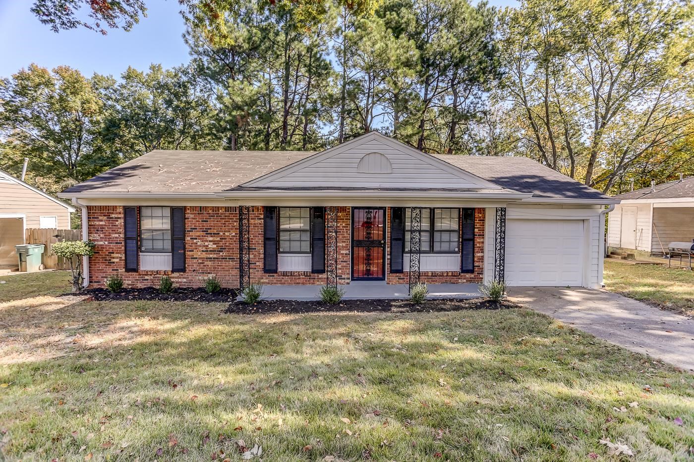 Ranch-style home with a front yard, covered porch, and a garage