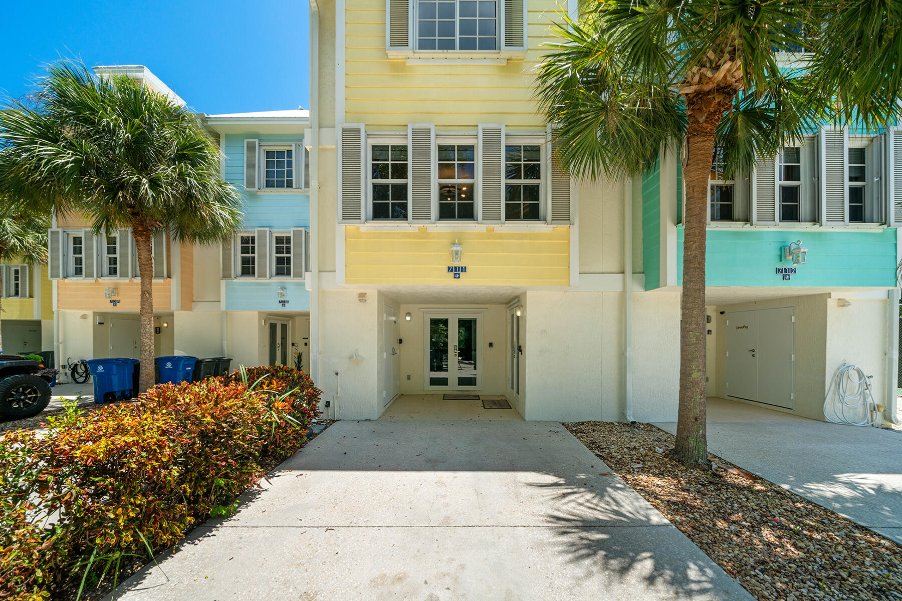 a front view of a house with a yard and palm trees