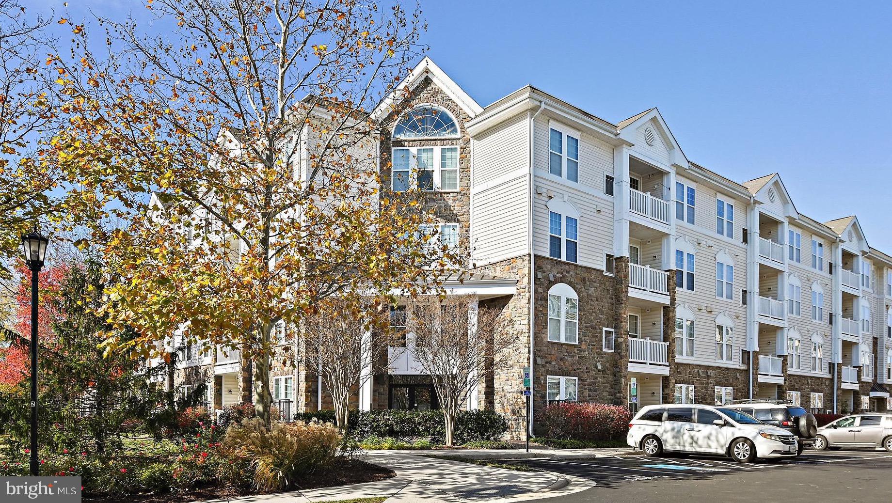 a front view of a building with lot of cars and trees