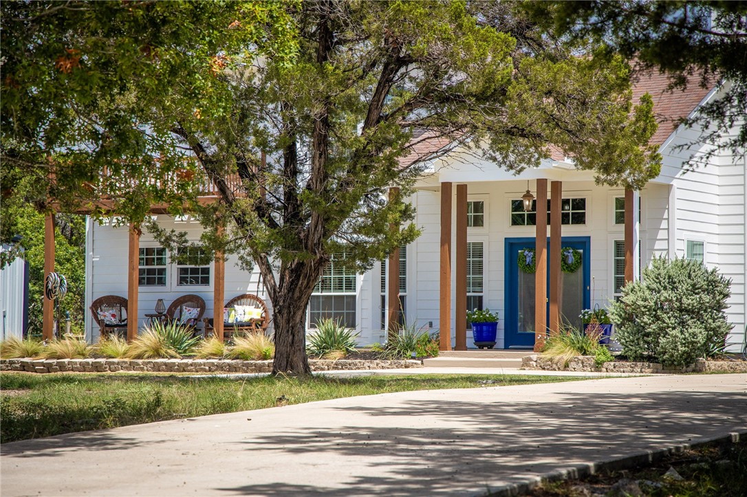 a front view of a house with garden and trees