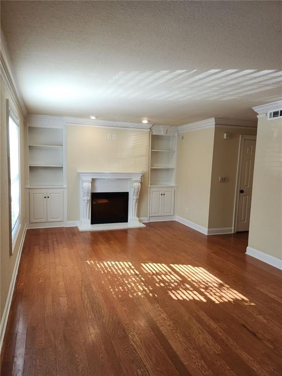 an empty room with a fireplace and bathroom with wooden floor