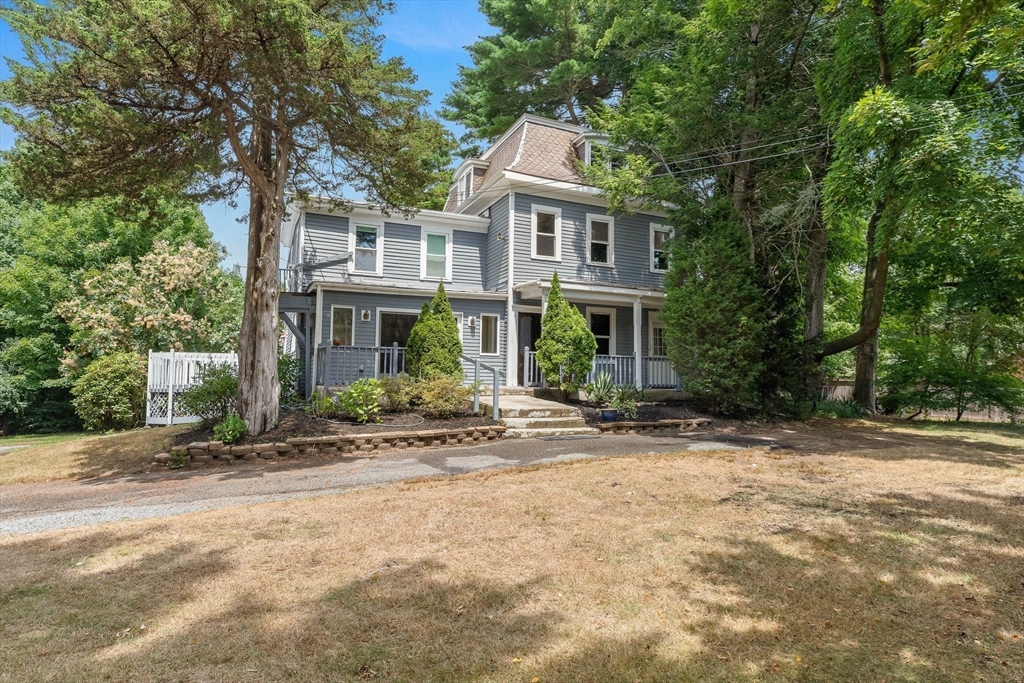 a front view of a house with a yard and potted plants