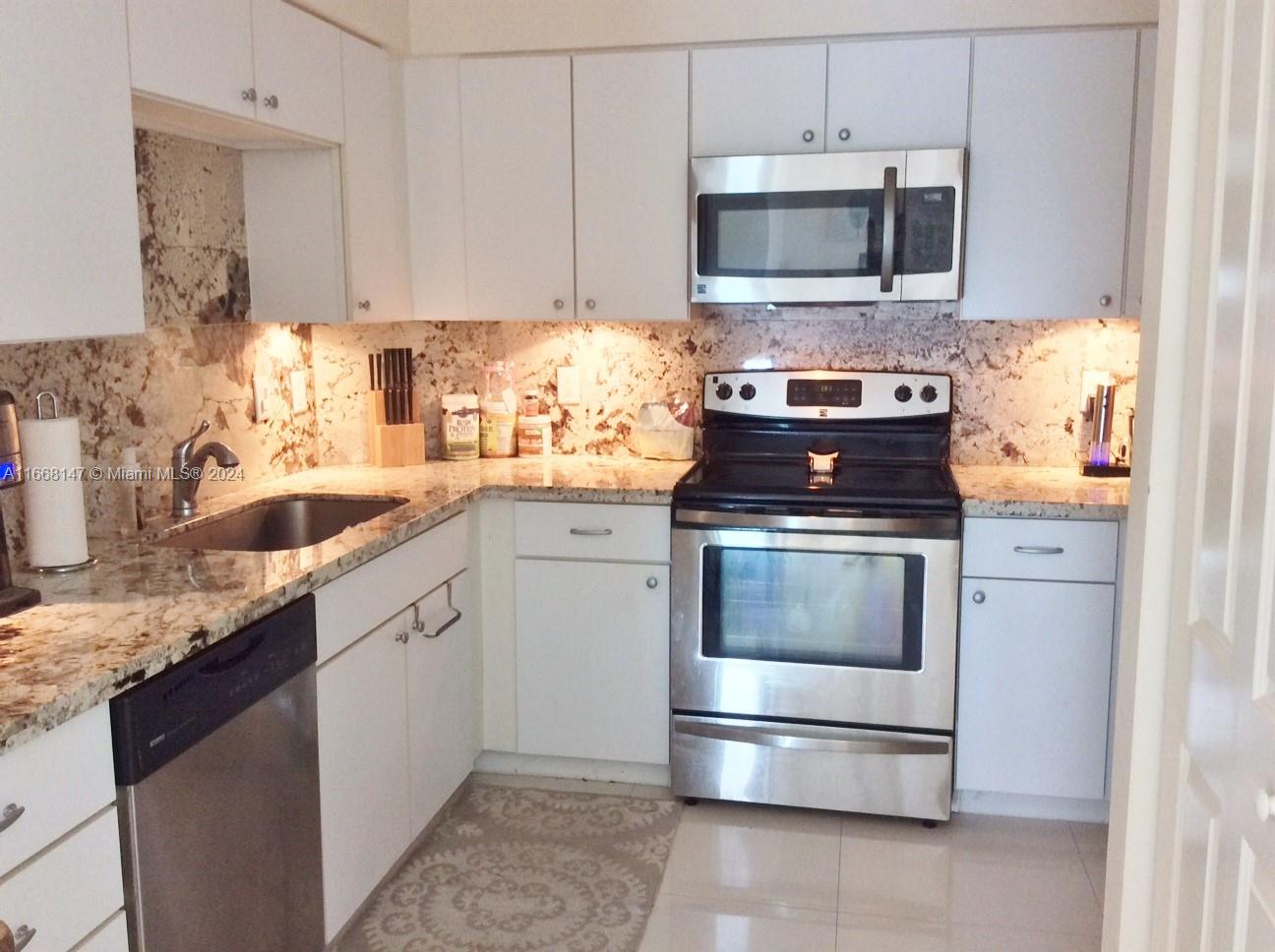 a kitchen with granite countertop white cabinets and stainless steel appliances