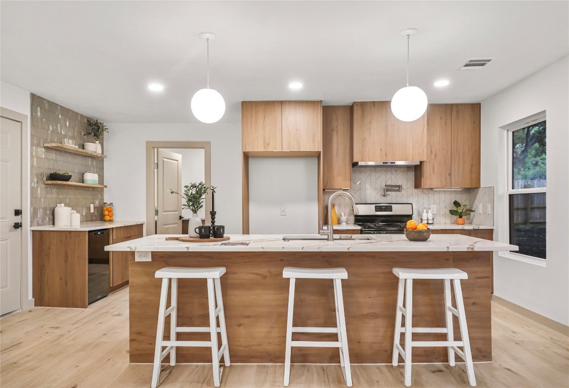 Modern, sleek European cabinetry and hardware. Massive 9 ft long center island with quartz countertops and modern pendants. Kitchen is equipped with SS appliances & a small beverage fridge.