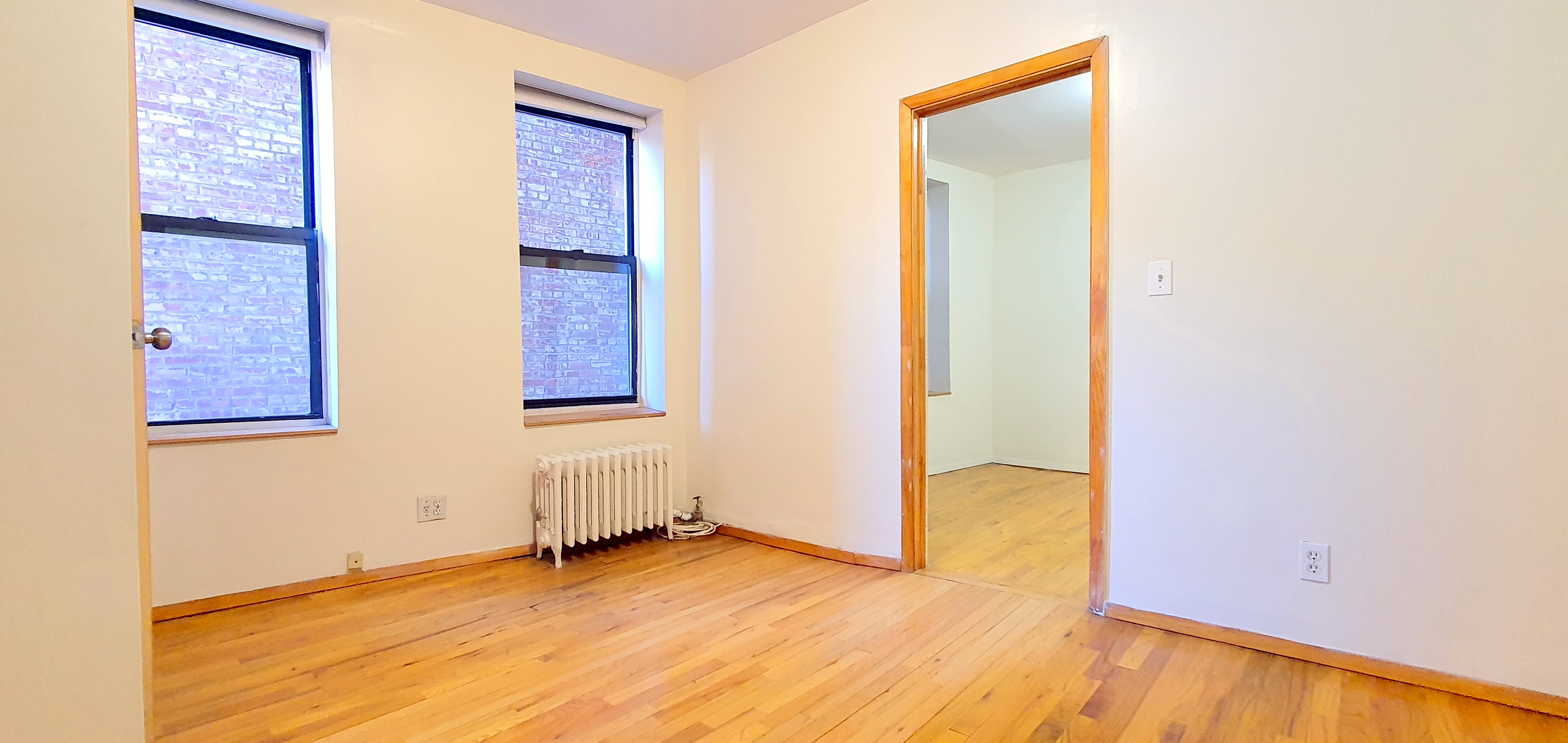 a view of an empty room with wooden floor and closet