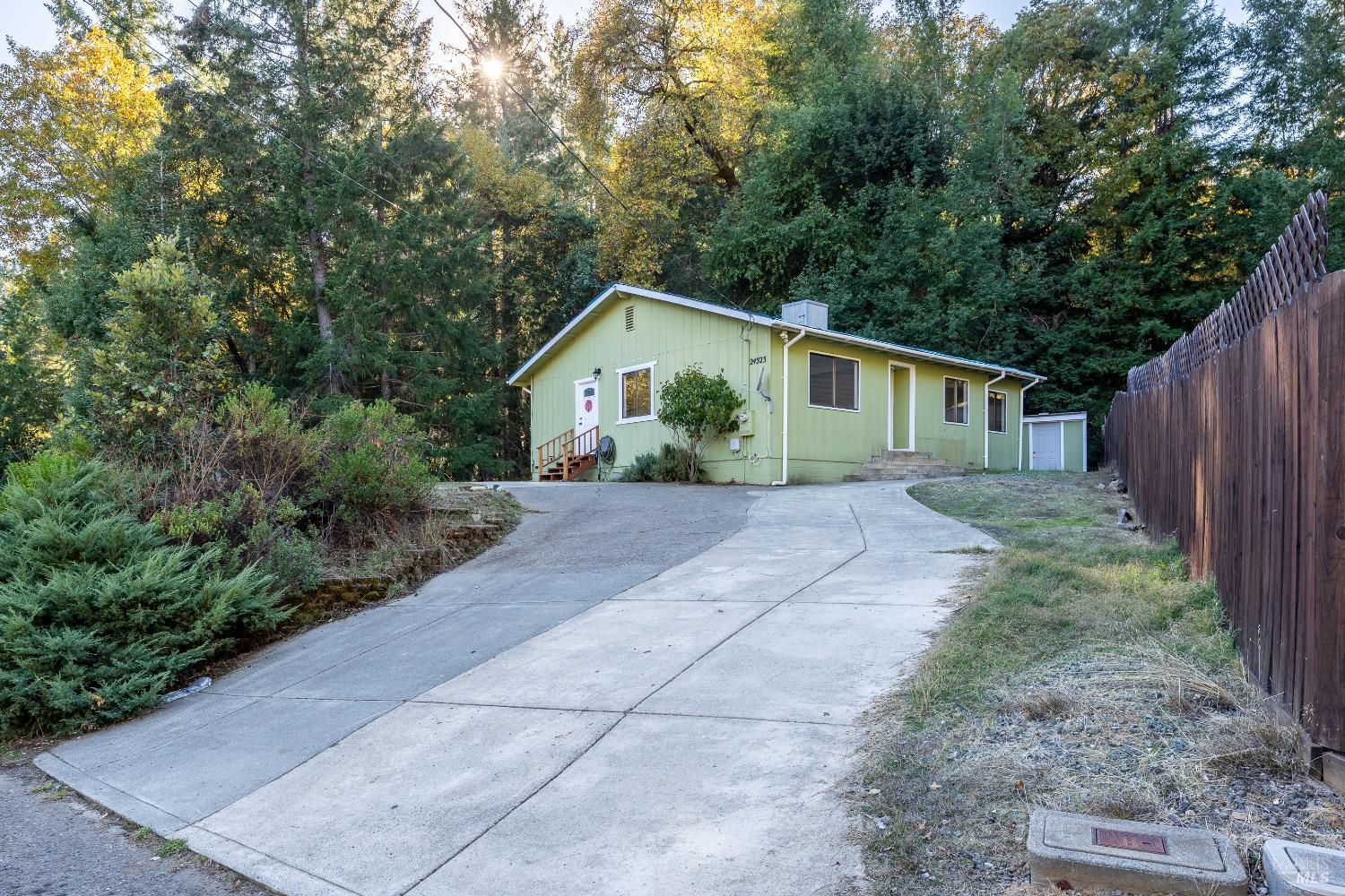 a view of house with a yard and large trees