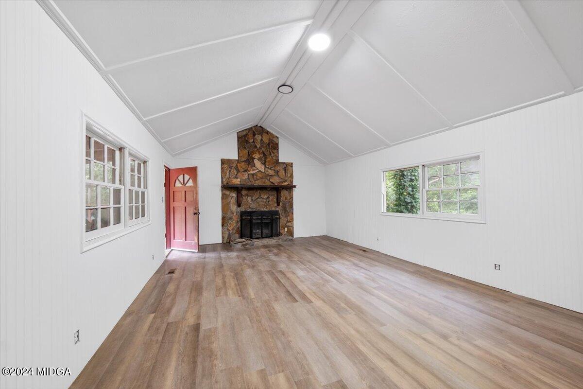 an empty room with windows a fireplace and wooden floor