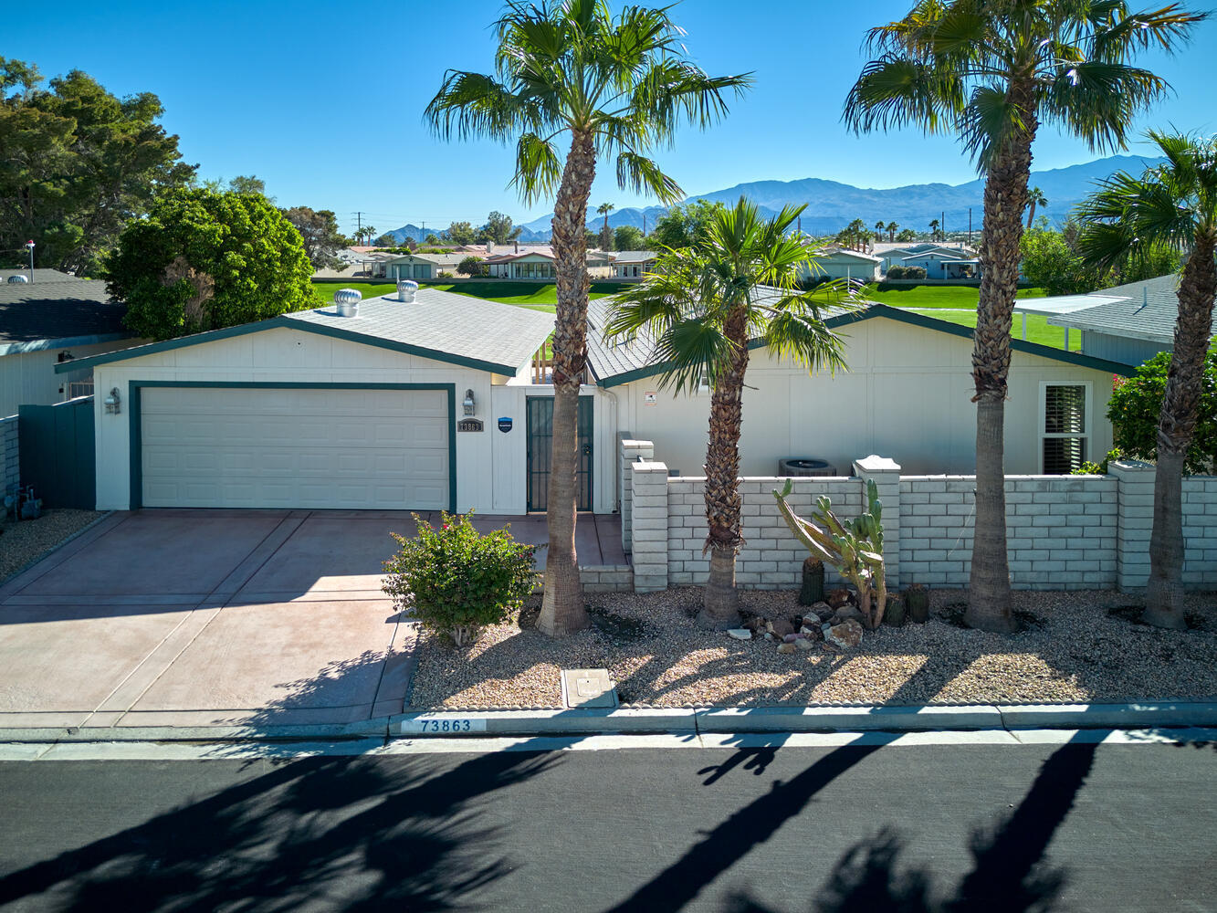 a view of a house with a yard and palm trees