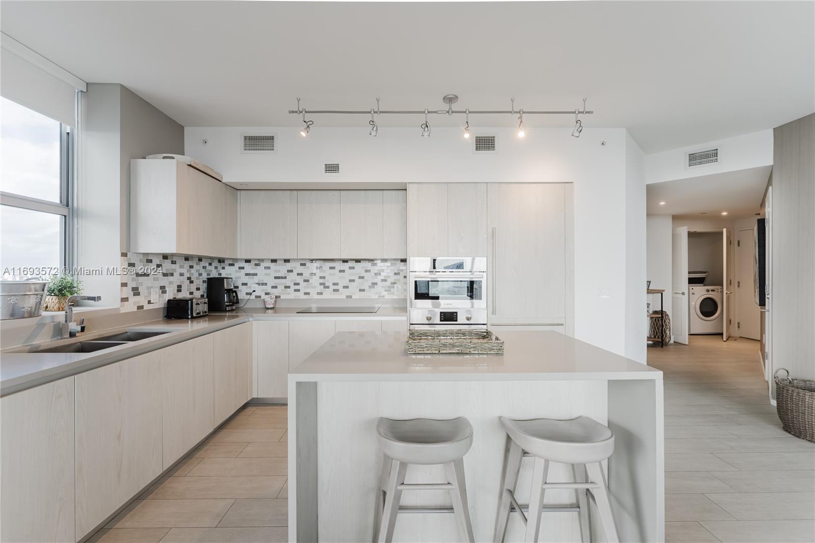 a kitchen with stainless steel appliances a sink a stove and white cabinets