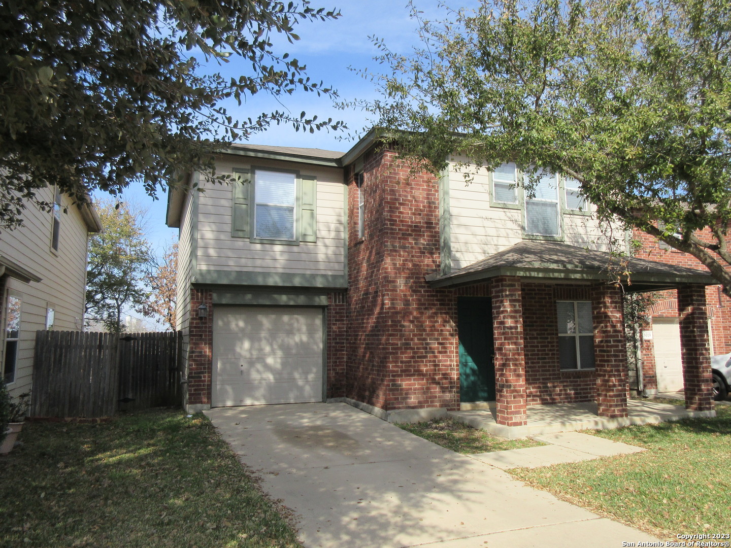 a front view of a house with a garden and tree