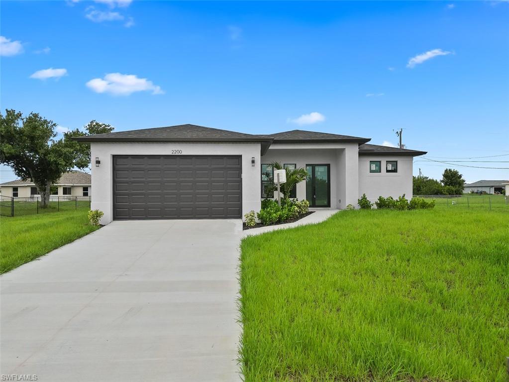 View of front of property featuring a garage and a front lawn