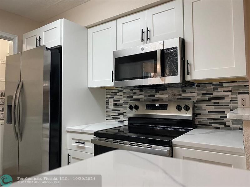 a kitchen with stainless steel appliances a stove a microwave a sink and cabinets