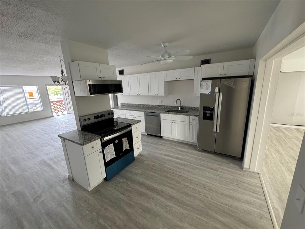 a kitchen with a refrigerator a stove top oven and wooden floor