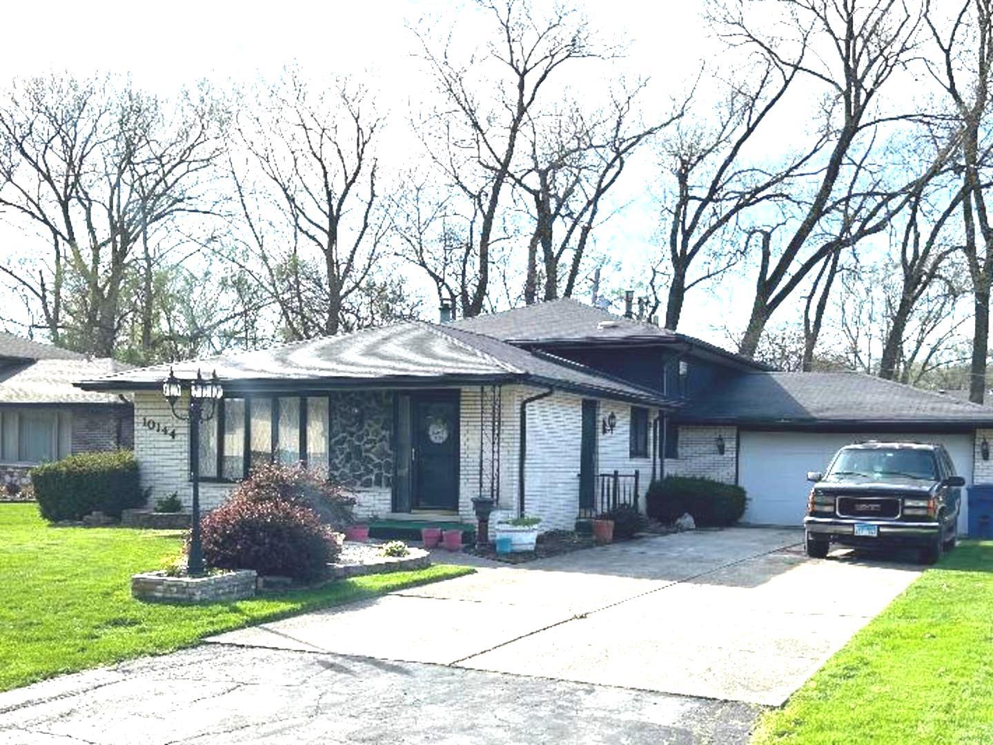 a front view of a house with a garden and trees