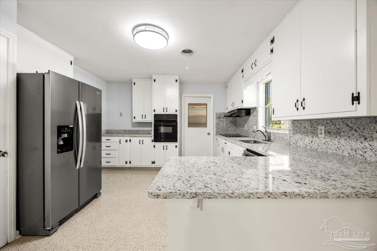 a kitchen with stainless steel appliances granite countertop a refrigerator a stove and white cabinets