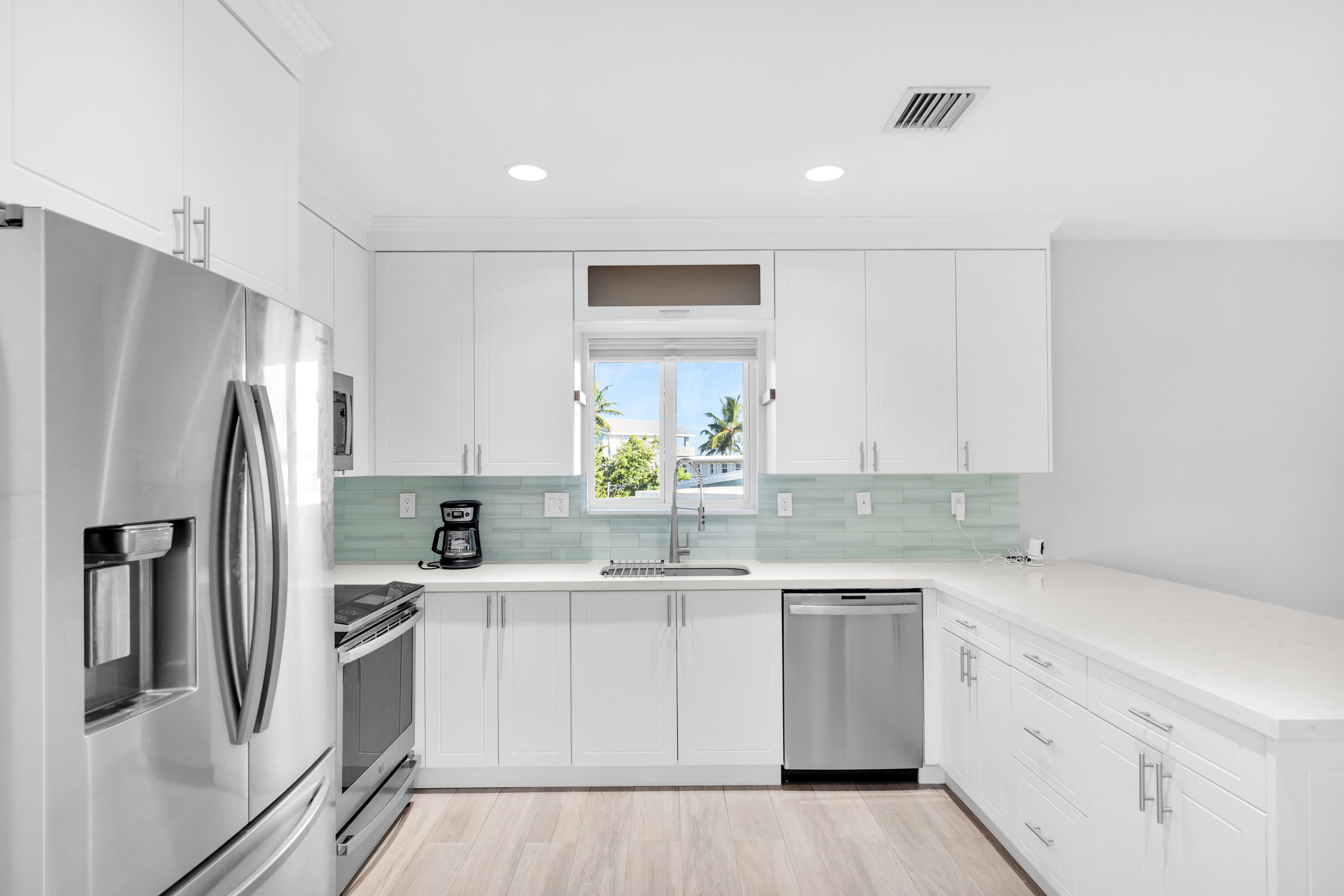 a kitchen with stainless steel appliances a refrigerator sink and white cabinets