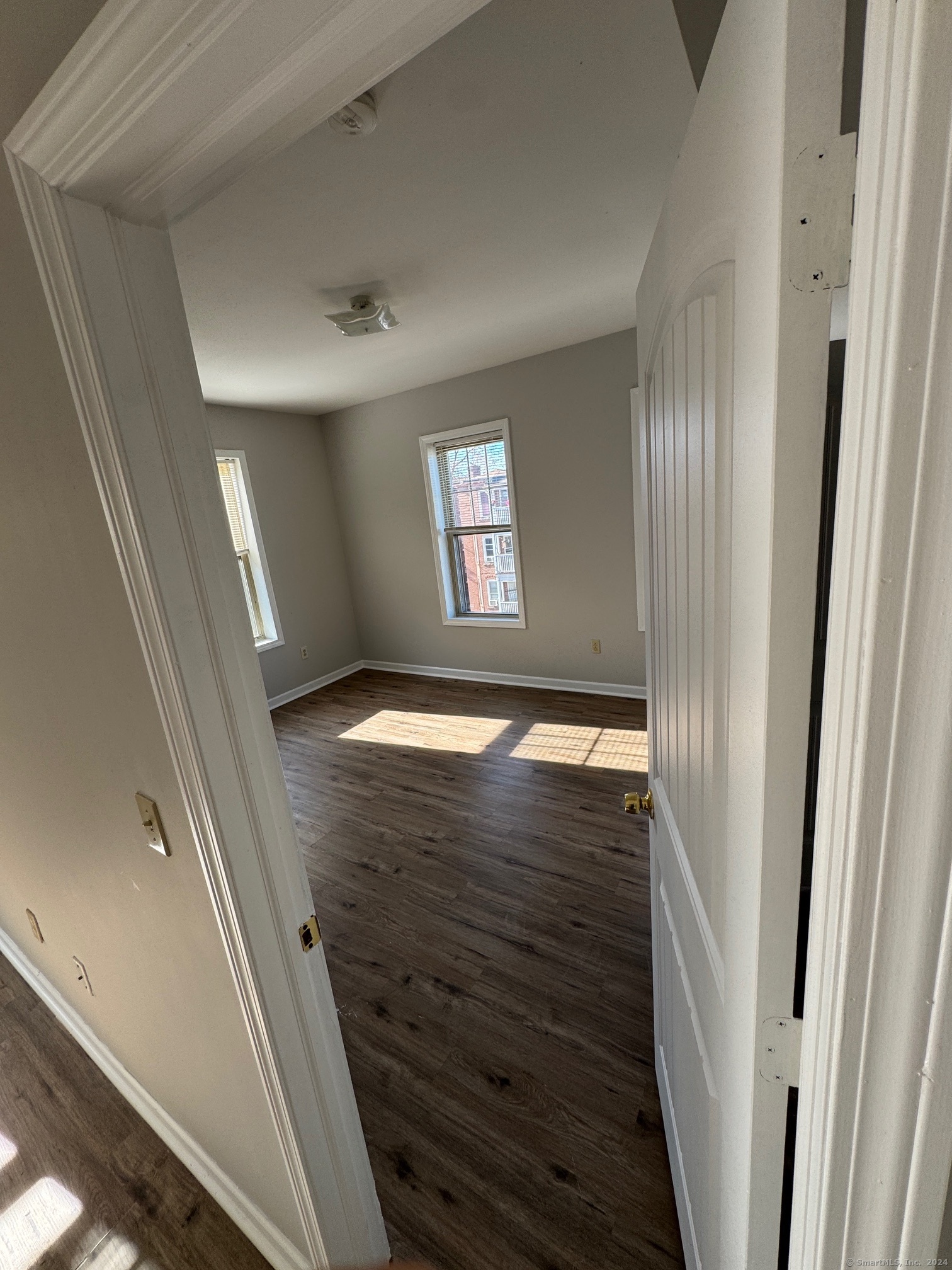 a view of an empty room with wooden floor and a window