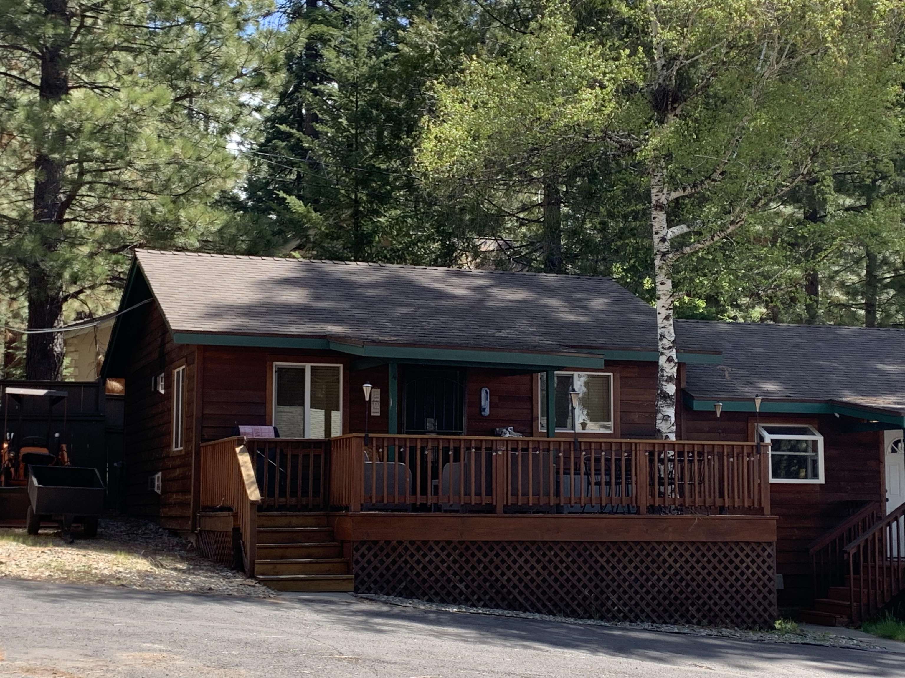 a view of house with deck outdoor seating and covered with trees