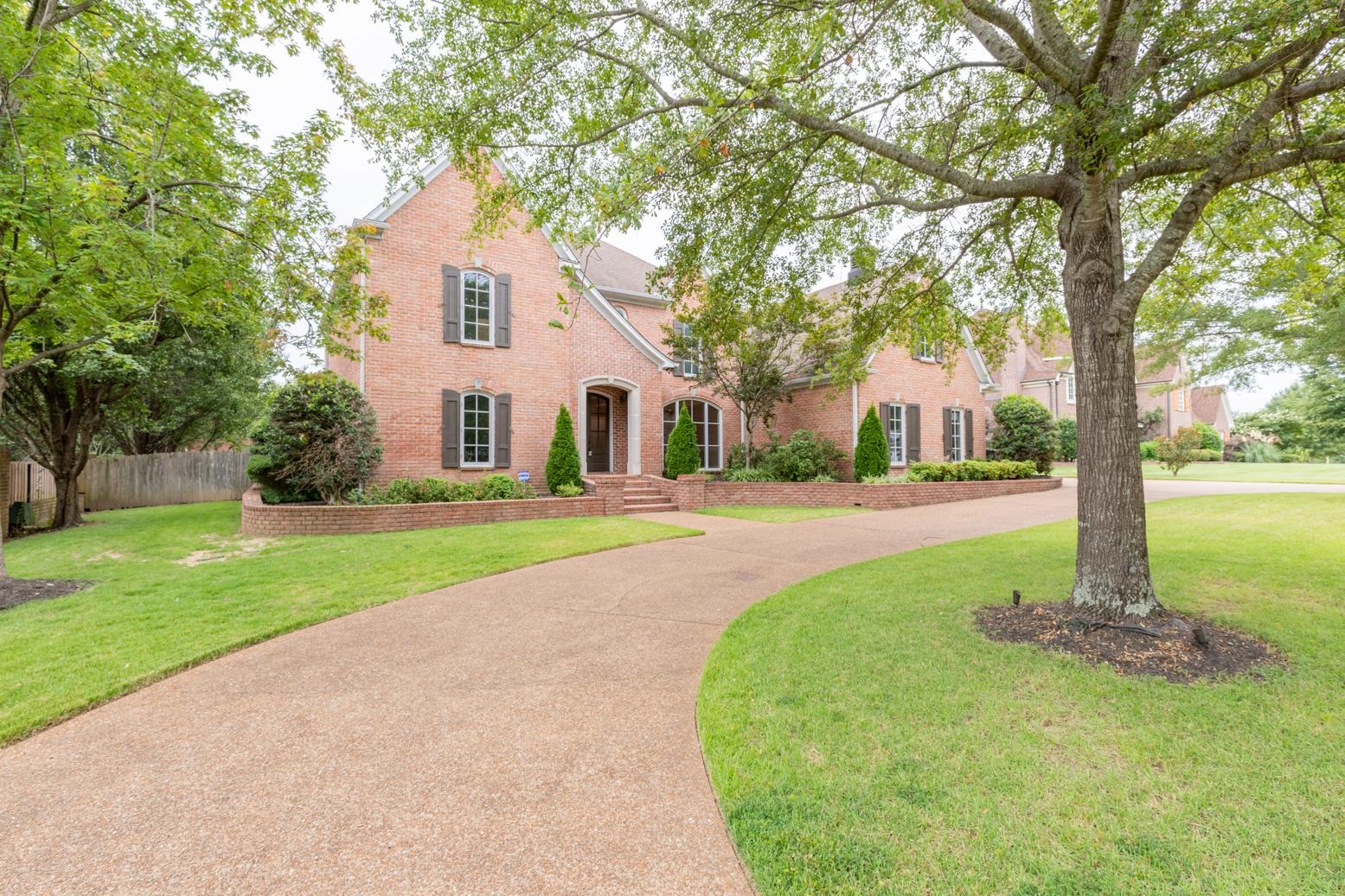 a front view of a house with garden and trees