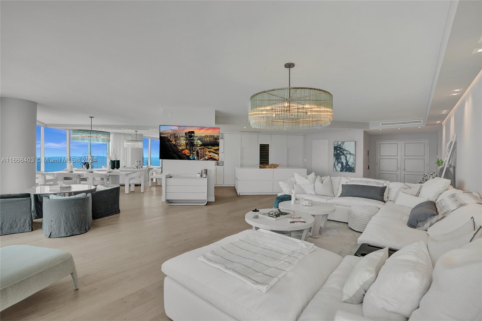 a living room with furniture a chandelier and kitchen view