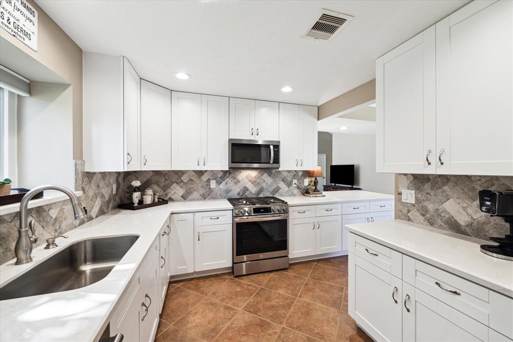 a kitchen with a sink stove and white cabinets