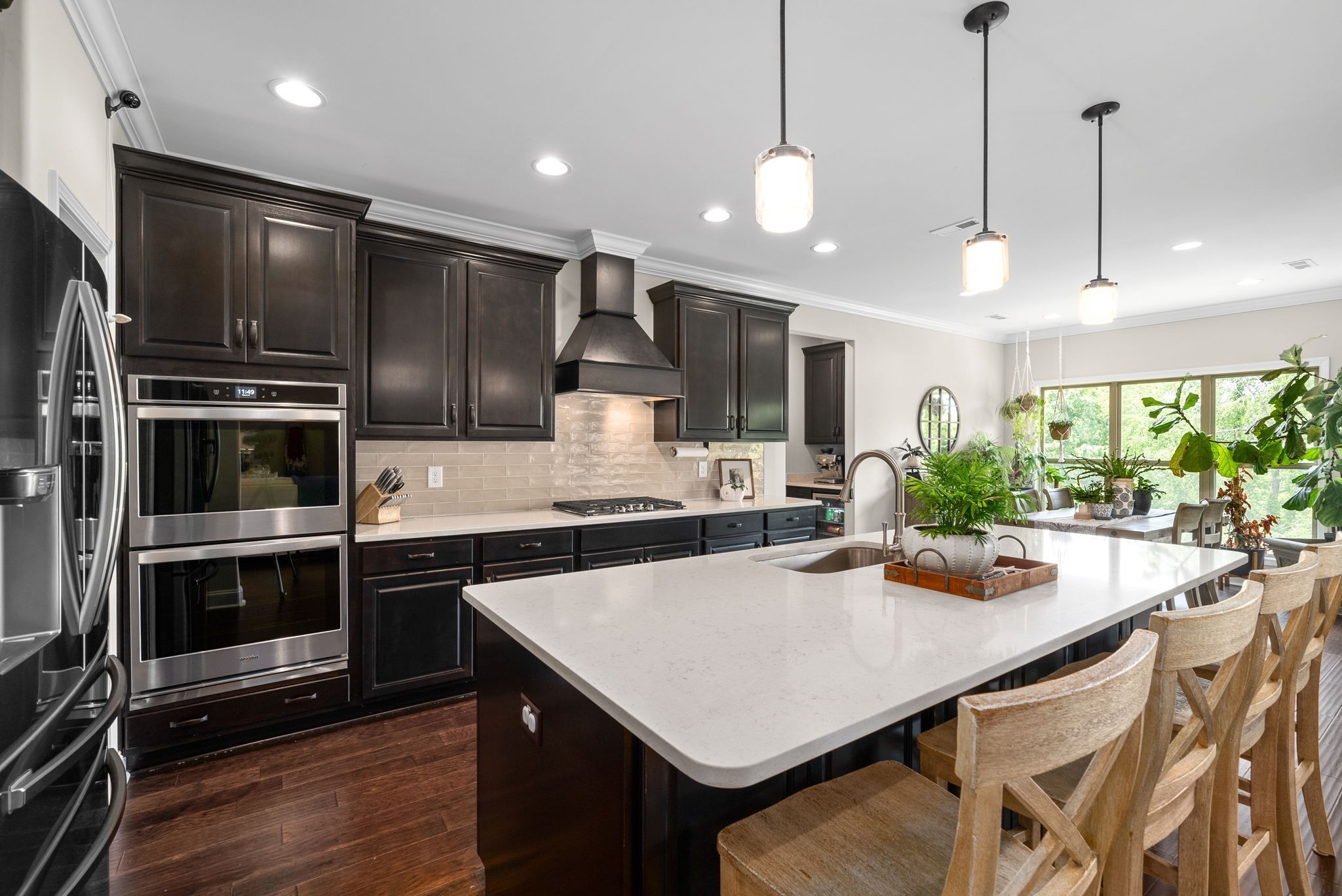 a kitchen with stainless steel appliances kitchen island granite countertop a stove a refrigerator a sink a kitchen island with chairs and wooden floor